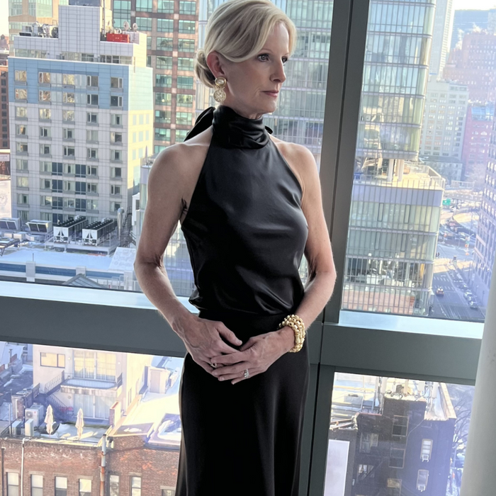 Woman in a black dress standing in front of a cityscape view