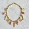 Gold necklace with pink charms on a marble surface