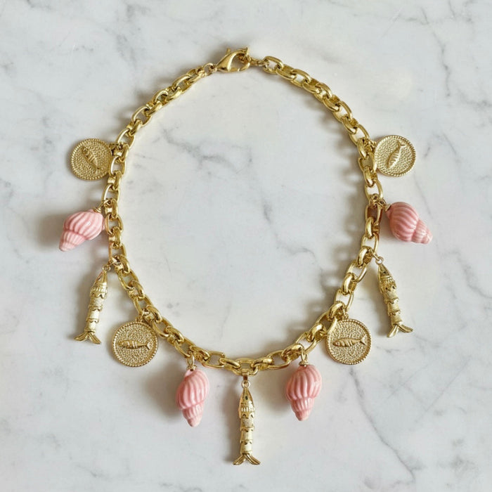 Gold necklace with pink charms on a marble surface