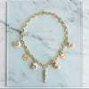 Gold necklace with various charms on a marble surface
