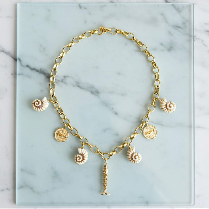 Gold necklace with various charms on a marble surface