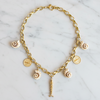 Gold chain necklace with various charms on a marble surface