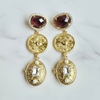 Gold earrings with gemstones on a marble surface