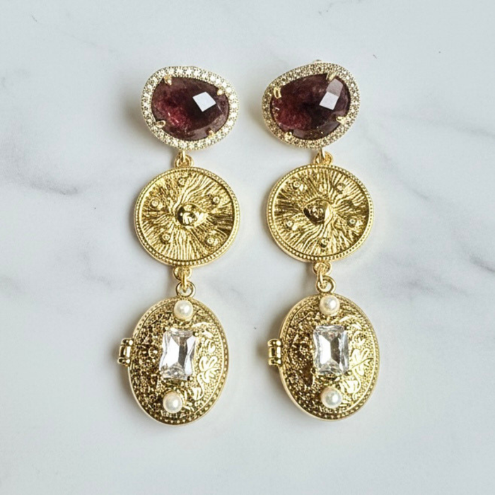 Gold earrings with gemstones on a marble surface