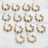 Set of gold hoop earrings with colorful gemstones on a marble surface