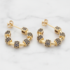 Gold hoop earrings with embedded blue stones on a light gray background