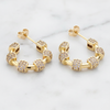 Gold hoop earrings with embedded stones on a light background