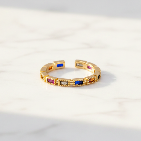 Gold ring with colorful gemstones on a light gray background