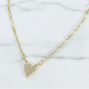 Gold necklace with a heart-shaped pendant on a marble background