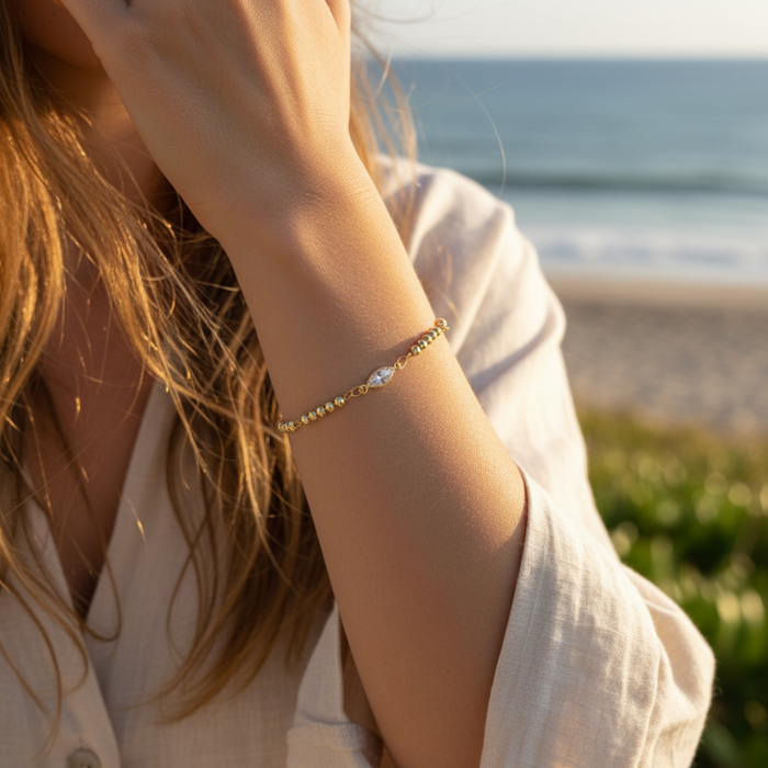 Person wearing a gold bracelet on a beach