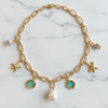 Gold chain necklace with charms on a marble background