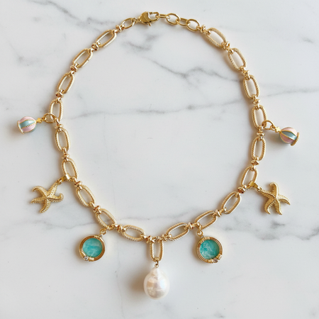 Gold chain necklace with charms on a marble background