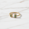 Gold ring with green gemstones on a light background