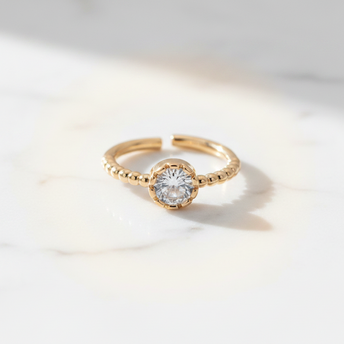 Gold ring with a diamond on a light gray background