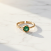 Gold ring with a green gemstone on a light background
