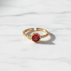 Gold ring with a red gemstone on a white background