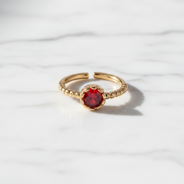 Gold ring with a red gemstone on a white background
