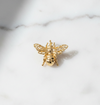 Gold bee-shaped brooch on a marble surface
