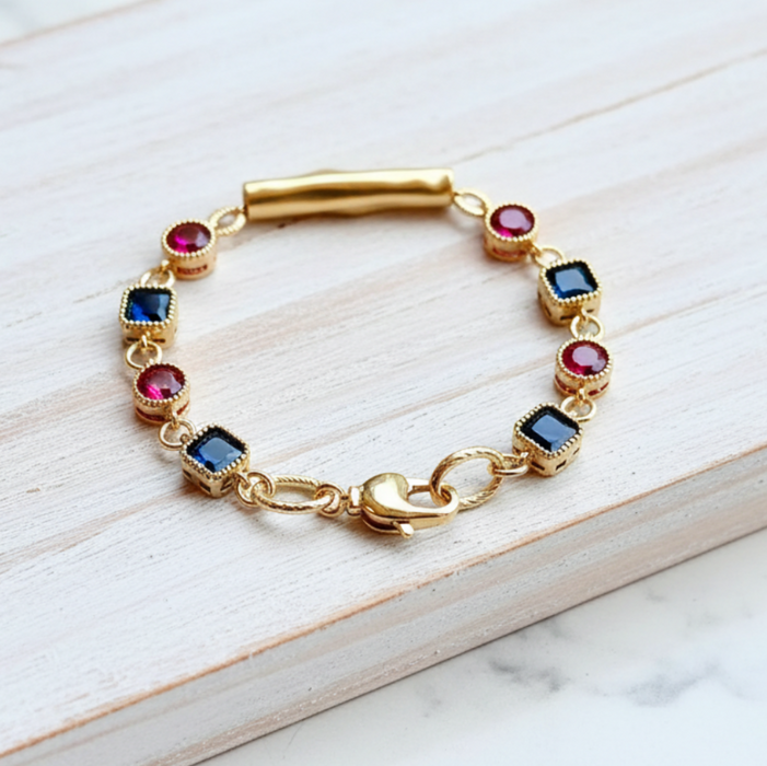 Gold bracelet with colorful gemstones on a light wooden surface