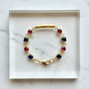 Gold bracelet with colorful gemstones on a marble surface
