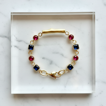 Gold bracelet with colorful gemstones on a marble surface