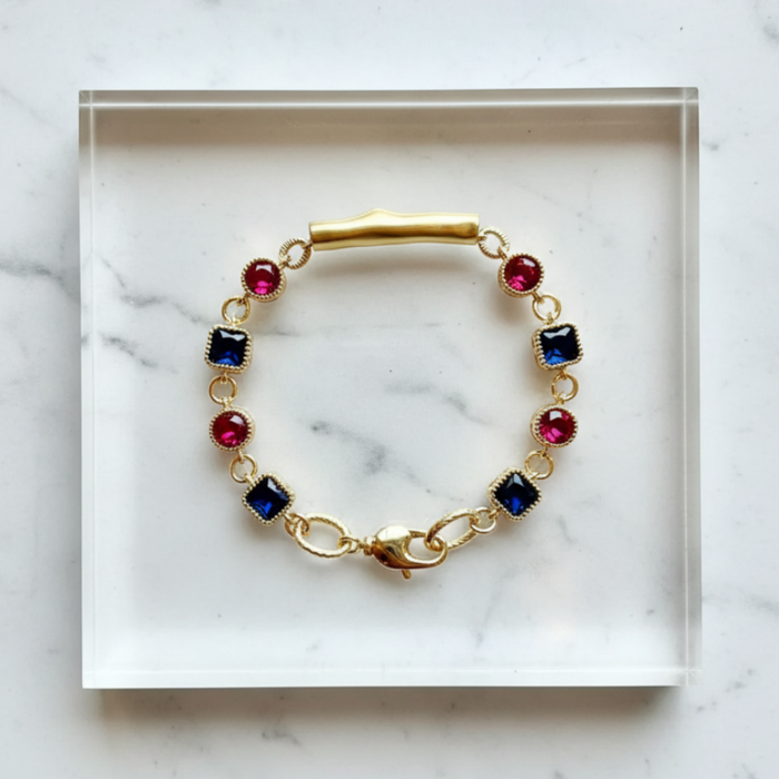 Gold bracelet with colorful gemstones on a marble surface