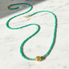 Turquoise beaded necklace with a gold clasp on a marble surface