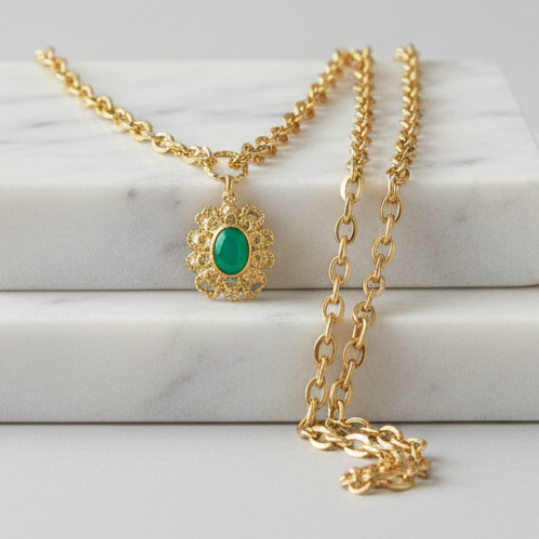 Gold necklace with a green pendant on a marble surface