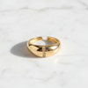 Gold ring with a small diamond on a white marble surface
