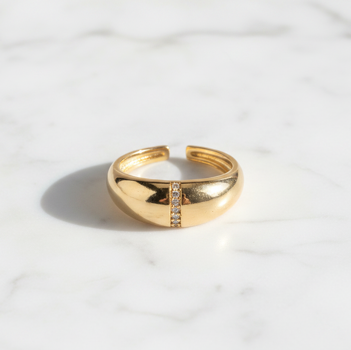 Gold ring with a small diamond on a white marble surface