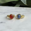 Two gold rings with gemstones on a marble surface
