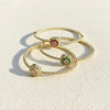 Set of gold bracelets with gemstone charms on a light background
