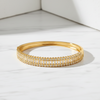 Gold bracelet with clear stones on a white surface