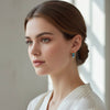 Woman wearing colorful earrings in a softly lit room