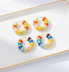 Colorful hoop earrings on a white tray with gold rim