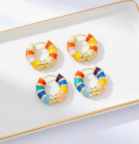 Colorful hoop earrings on a white tray with gold rim