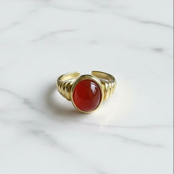 Gold ring with a red stone on a marble surface