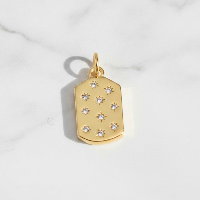Gold pendant with embedded diamonds on a light gray background