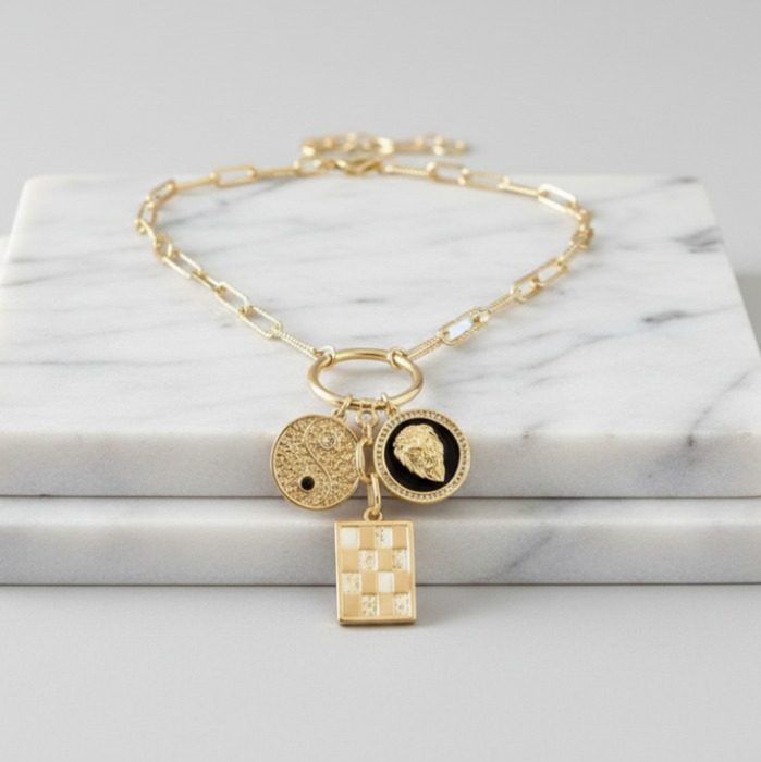 Gold necklace with charms on a marble surface