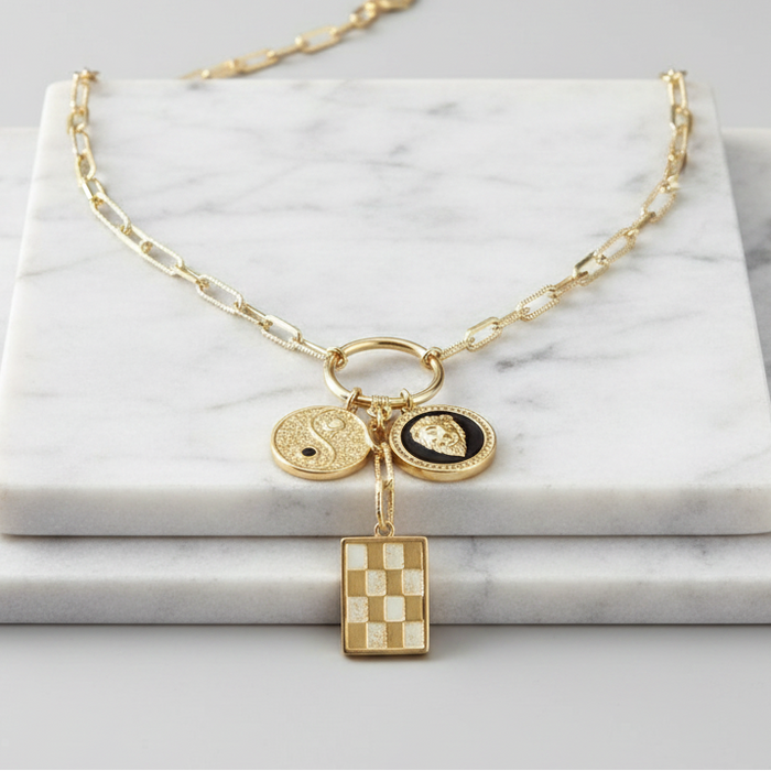 Gold necklace with charms on a marble surface