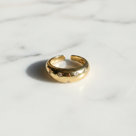 Gold ring with small stones on a marble surface