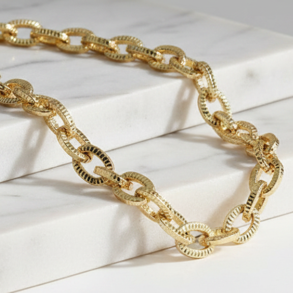 Gold chain necklace on a white marble surface