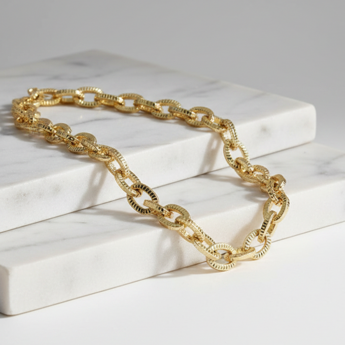 Gold chain necklace on a white marble surface