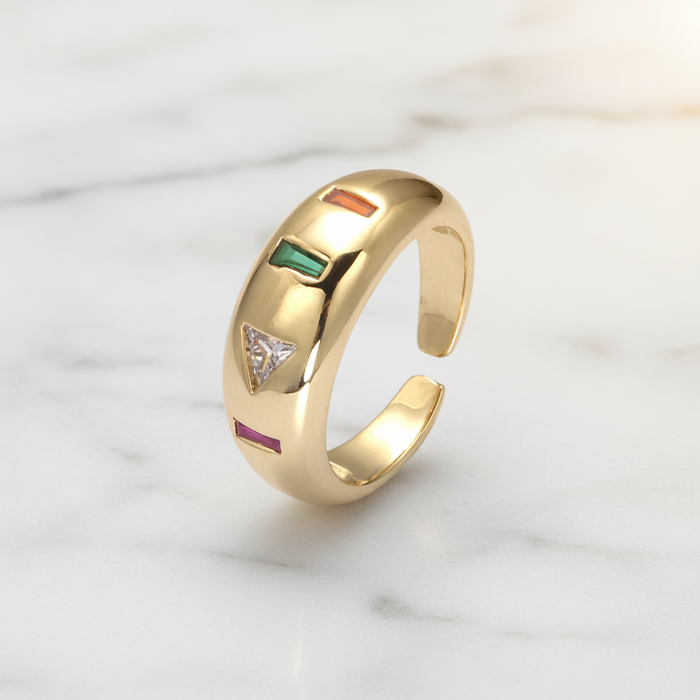 Gold ring with colored stones on a marble surface