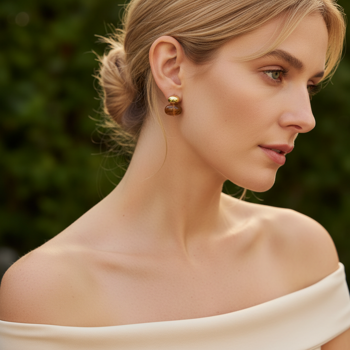 Woman wearing gold earrings with a blurred green background