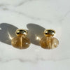 Pair of gold and clear earrings on a marble surface