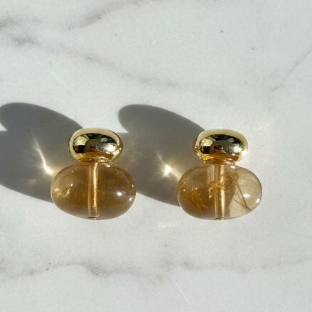 Pair of gold and clear earrings on a marble surface