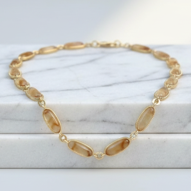 Gold necklace on a marble surface with soft lighting