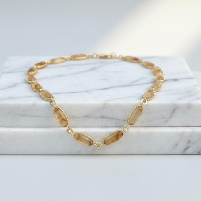 Gold necklace on a marble surface with soft lighting