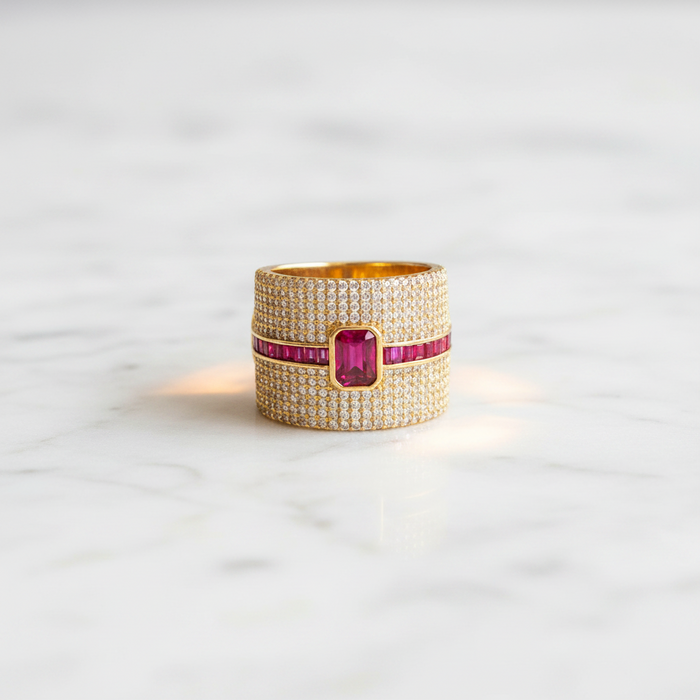 Gold ring with a red gemstone on a light gray background
